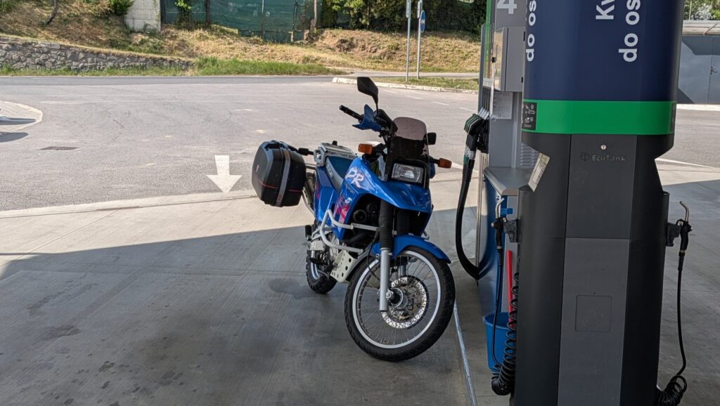 How to Create Your Motorcycle Trip Budget Suzuki DR 800 S parked at a fuel station in Europe — motorcycle touring fuel costs