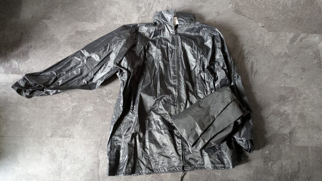 Compact packable rain gear for motorcycle touring showing compressed size in stuff sack and full rain jacket and pants
