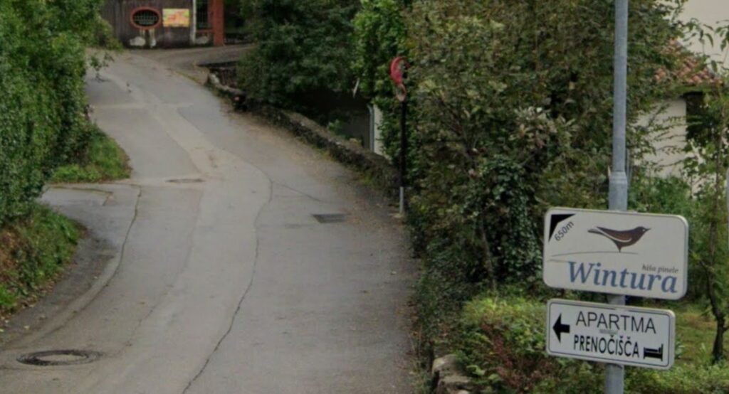 How to Find Cheap Accommodation for Motorcycle Touring Rural accommodation sign on a remote road in Europe — finding budget accommodation on the road