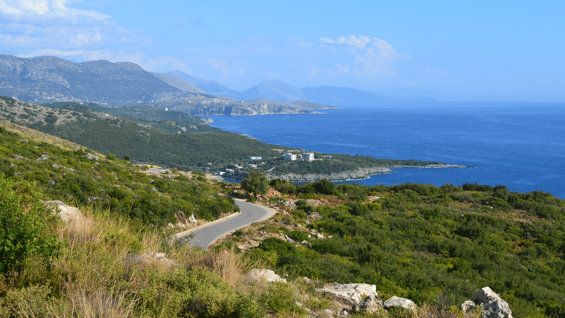 Albania Motorcycle Travel Guide: The Balkans' Hidden Gem Albanian Riviera clifftop coastal road with turquoise Ionian Sea below on the SH1 route for albania motorcycle travel
