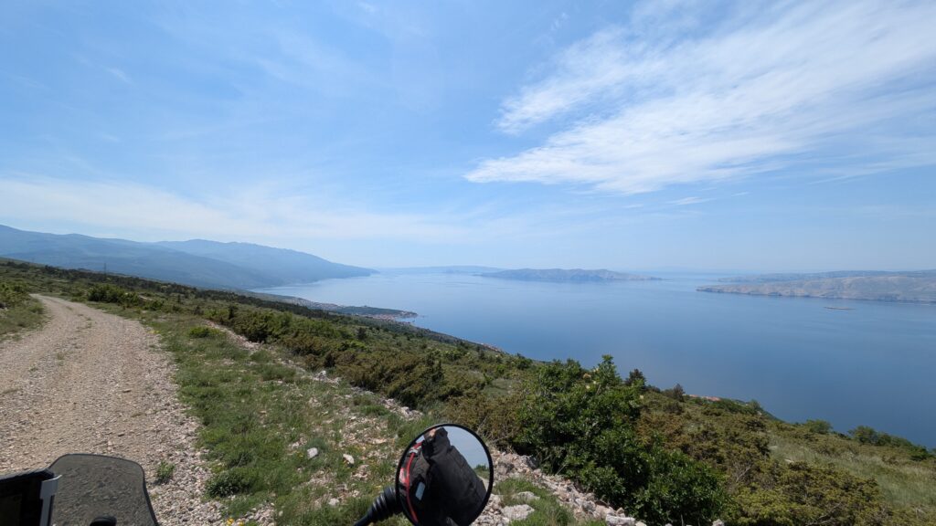 Motorcycle touring on Croatian coastal road during golden hour with Adriatic Sea and islands in background