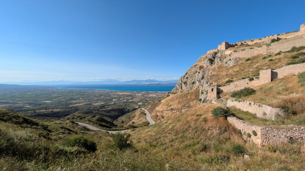 Budget Motorcycle Travel Europe: The Complete Guide Greece landscape with ancient ruins visible from the road — budget motorcycle travel Greece