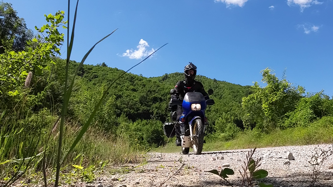 Camera on tripod positioned at road level with legs fully collapsed showing low perspective technique for motorcycle action self portrait photography 