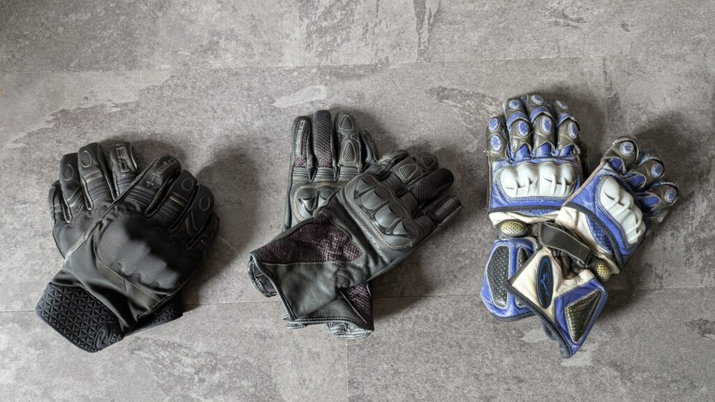 Motorcycle Rain Gear Guide: Stay Dry on Tour Multiple pairs of motorcycle gloves including waterproof touring gloves and overmitts showing two-pair strategy for wet weather touring