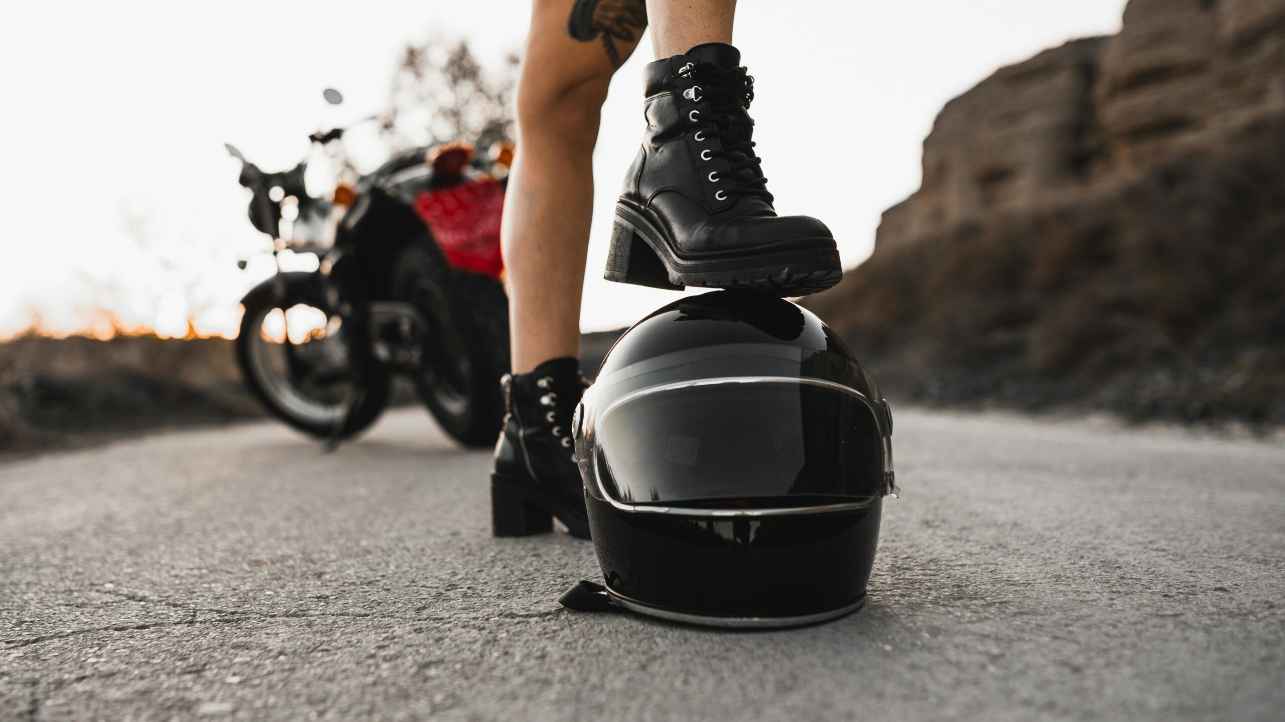 Motorcycle touring boots on pegs with scenic European mountain road stretching ahead