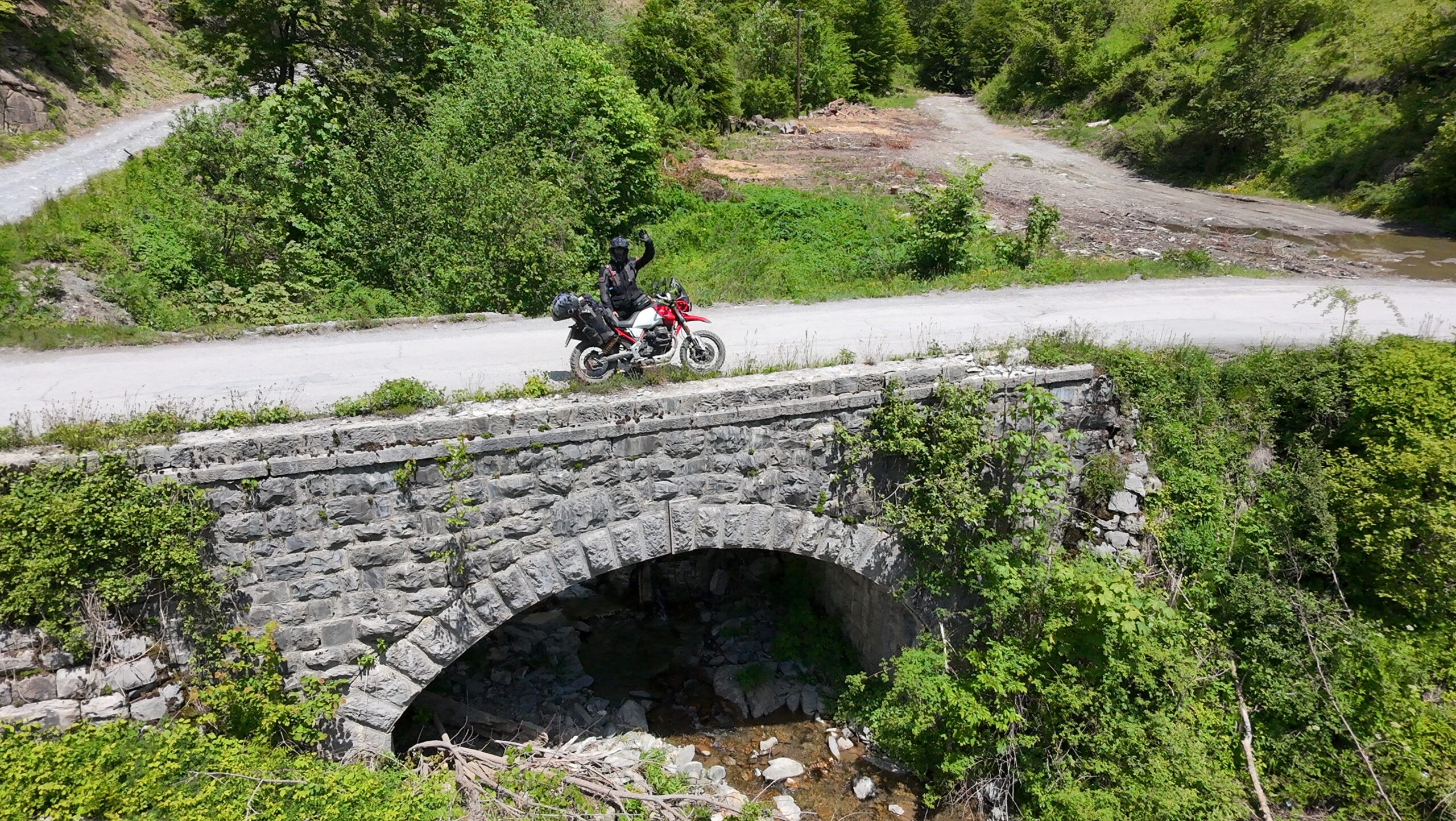 Travel Photography Aerial drone shot of Fritz and Derviša on a stone bridge in Albania — motorcycle travel photography from above