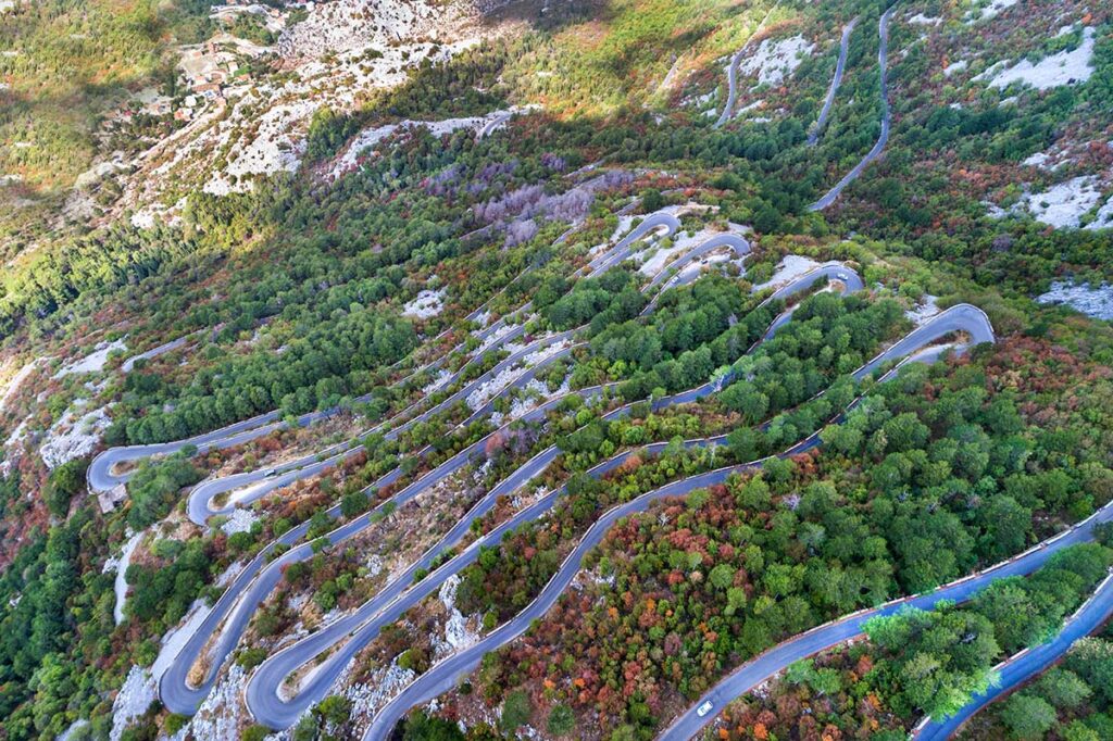 Bosnia and Montenegro Motorcycle Travel Guide Bay of Kotor serpentine road with 25 hairpins climbing Mount Lovćen above the bay in Montenegro showing iconic montenegro bosnia motorcycle route