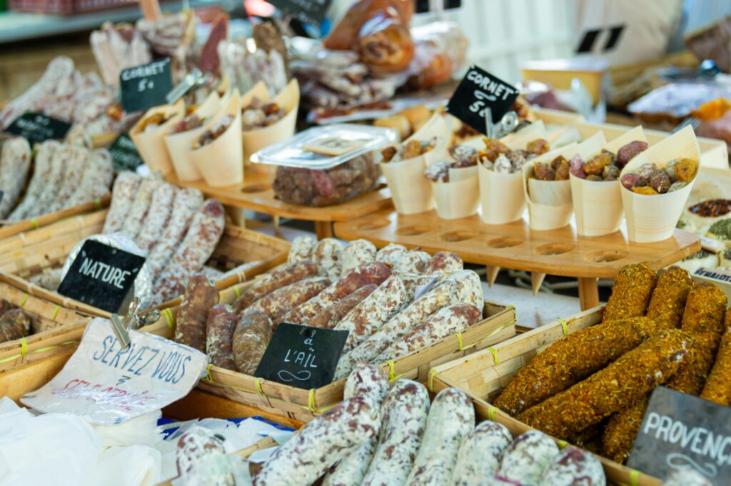 French weekly market with bread cheese and charcuterie stalls showing cheap local food option for motorcycle touring in France