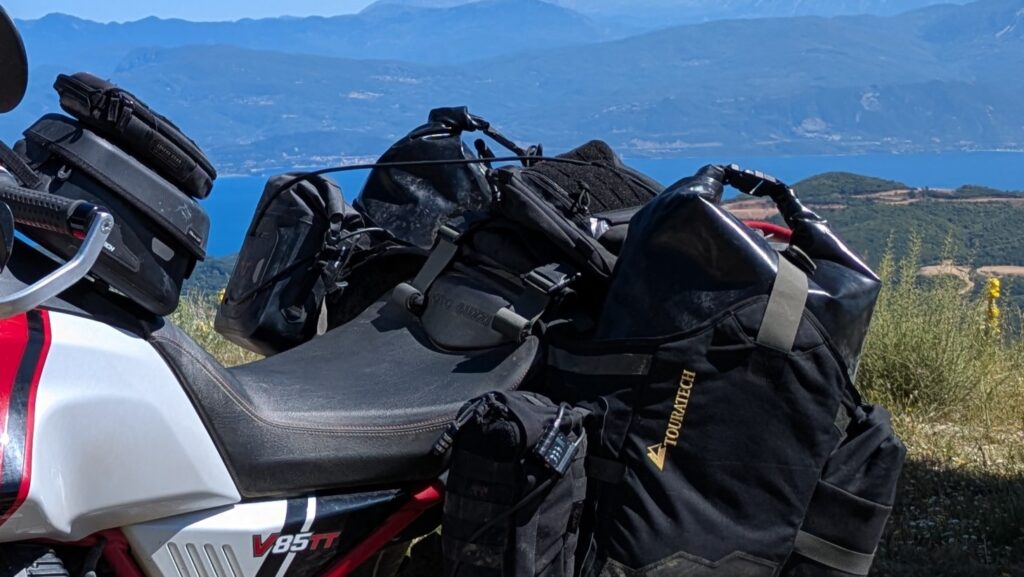 Cable lock threaded through motorcycle pannier handles and around frame showing basic anti-theft deterrent for motorcycle luggage security