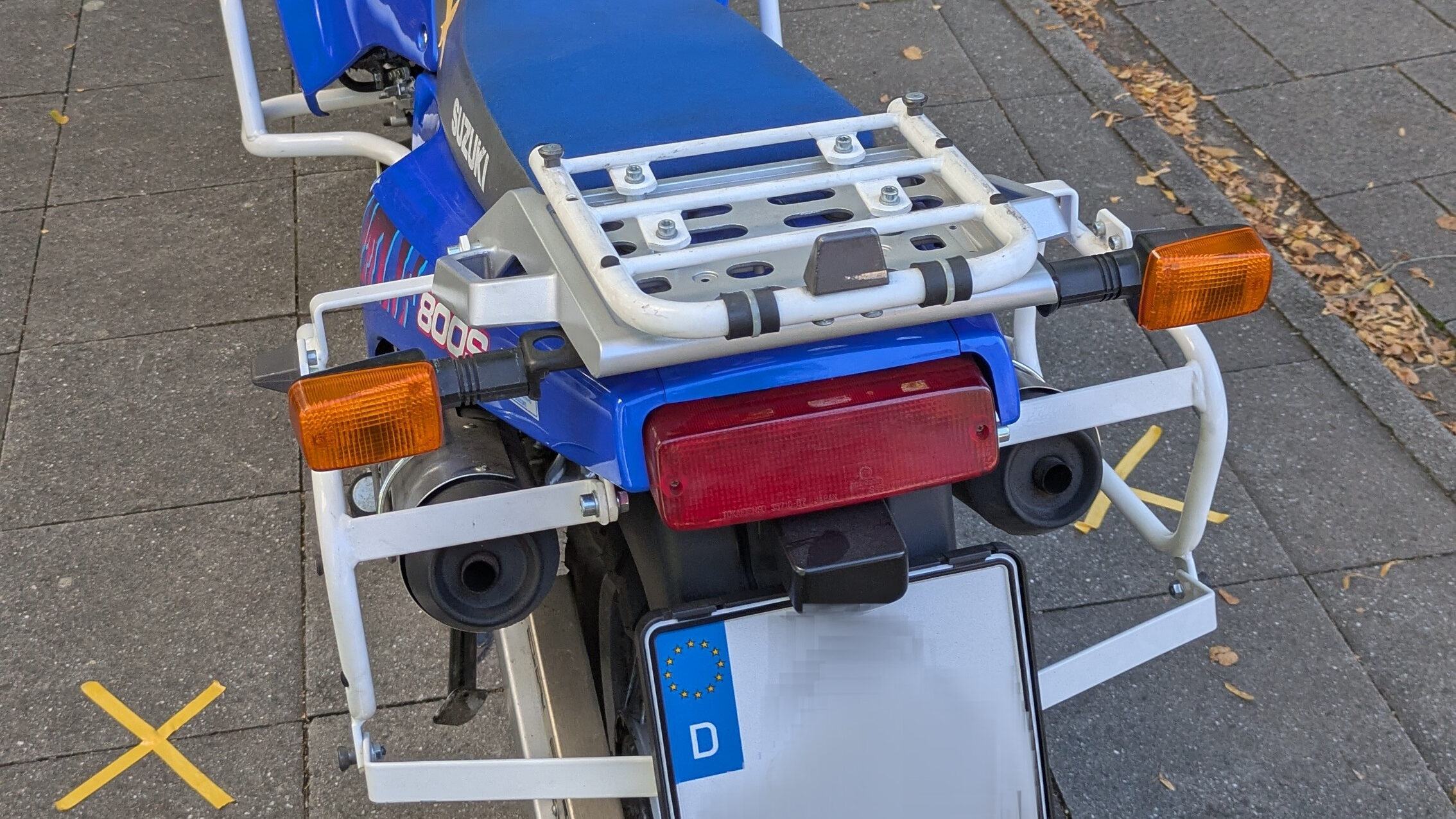 Motorcycle top case mounting plate fitted to rear of bike showing clean integration and keyed lock mechanism for secure top case attachment