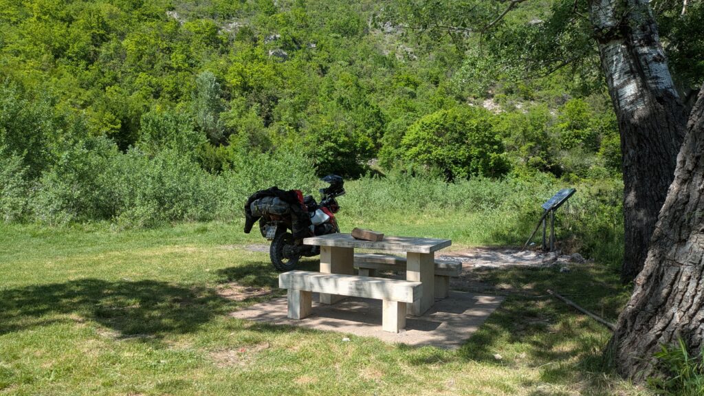 Motorcycle tourer enjoying simple cheap food at scenic European viewpoint showing reward of cheap food motorcycle touring strategy