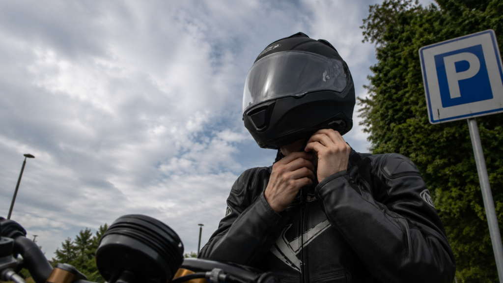 How to Choose the Right Motorcycle Helmet for Touring Rider adjusting a motorcycle helmet chin strap for proper fit